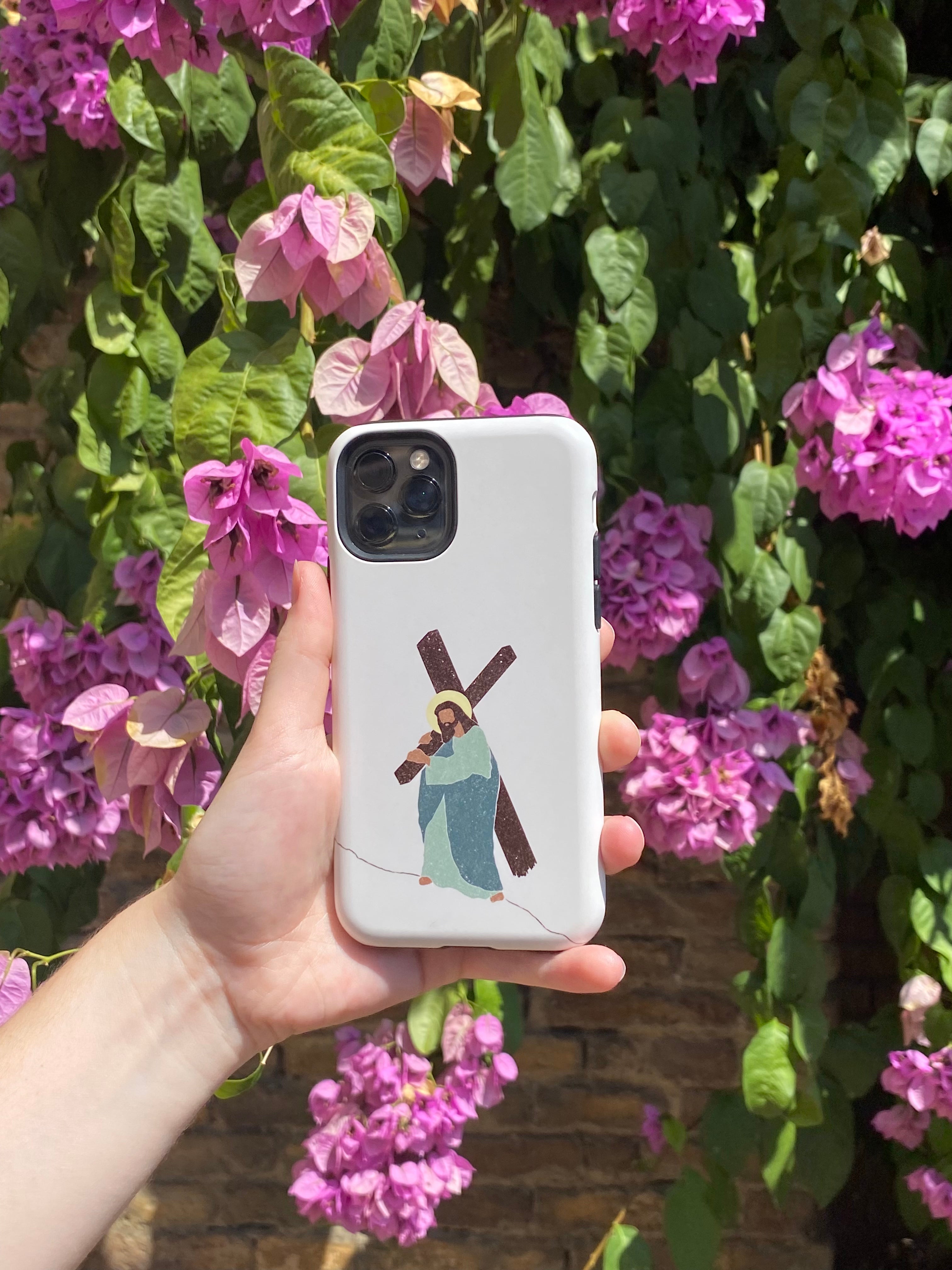iPhone case with an artistic portrayal of Jesus carrying the cross, set against a background of vibrant purple flowers.