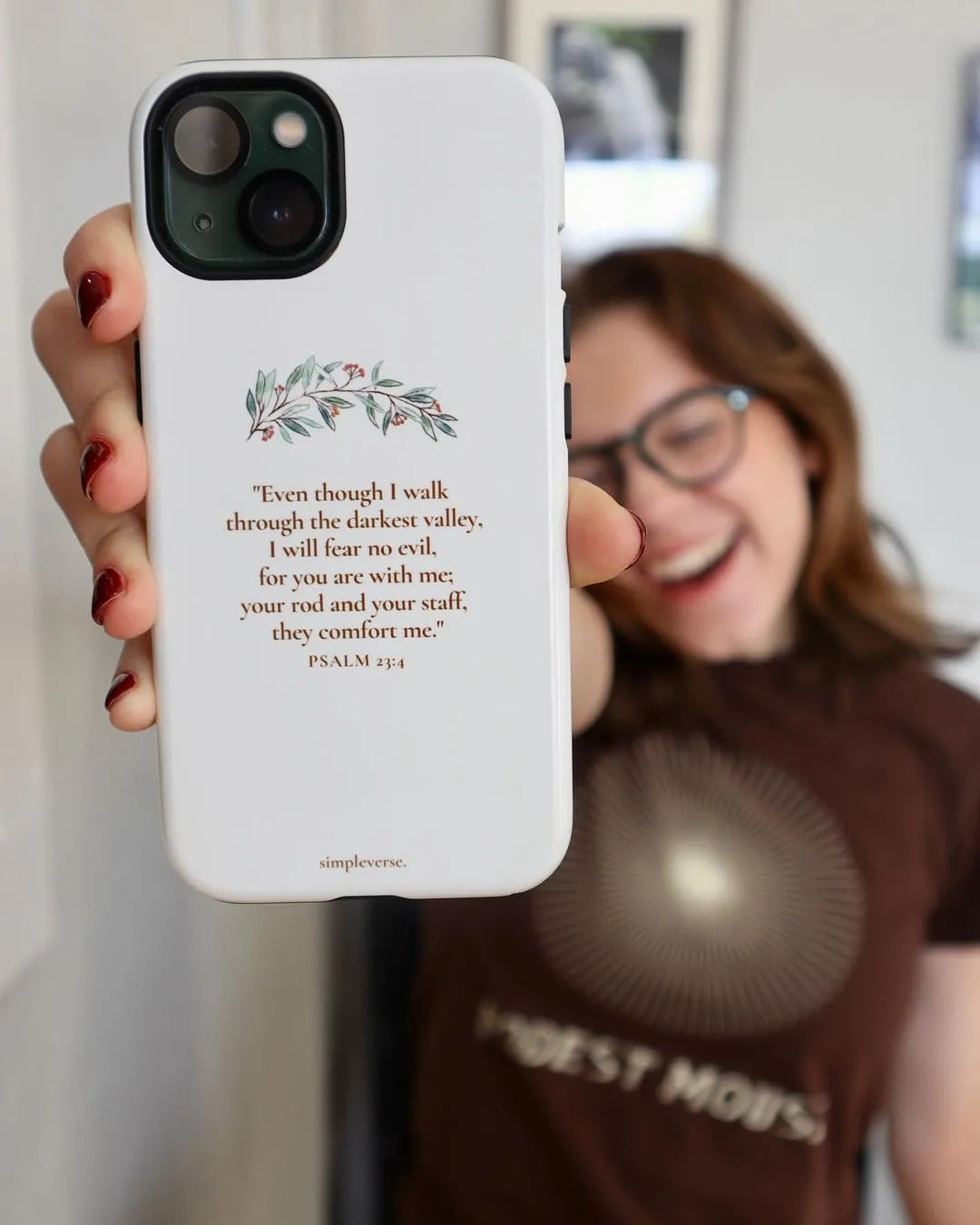 Model presenting a Christian-themed iPhone case to the camera, featuring an inspirational Bible verse, perfect for expressing faith through Simpleverse accessories.