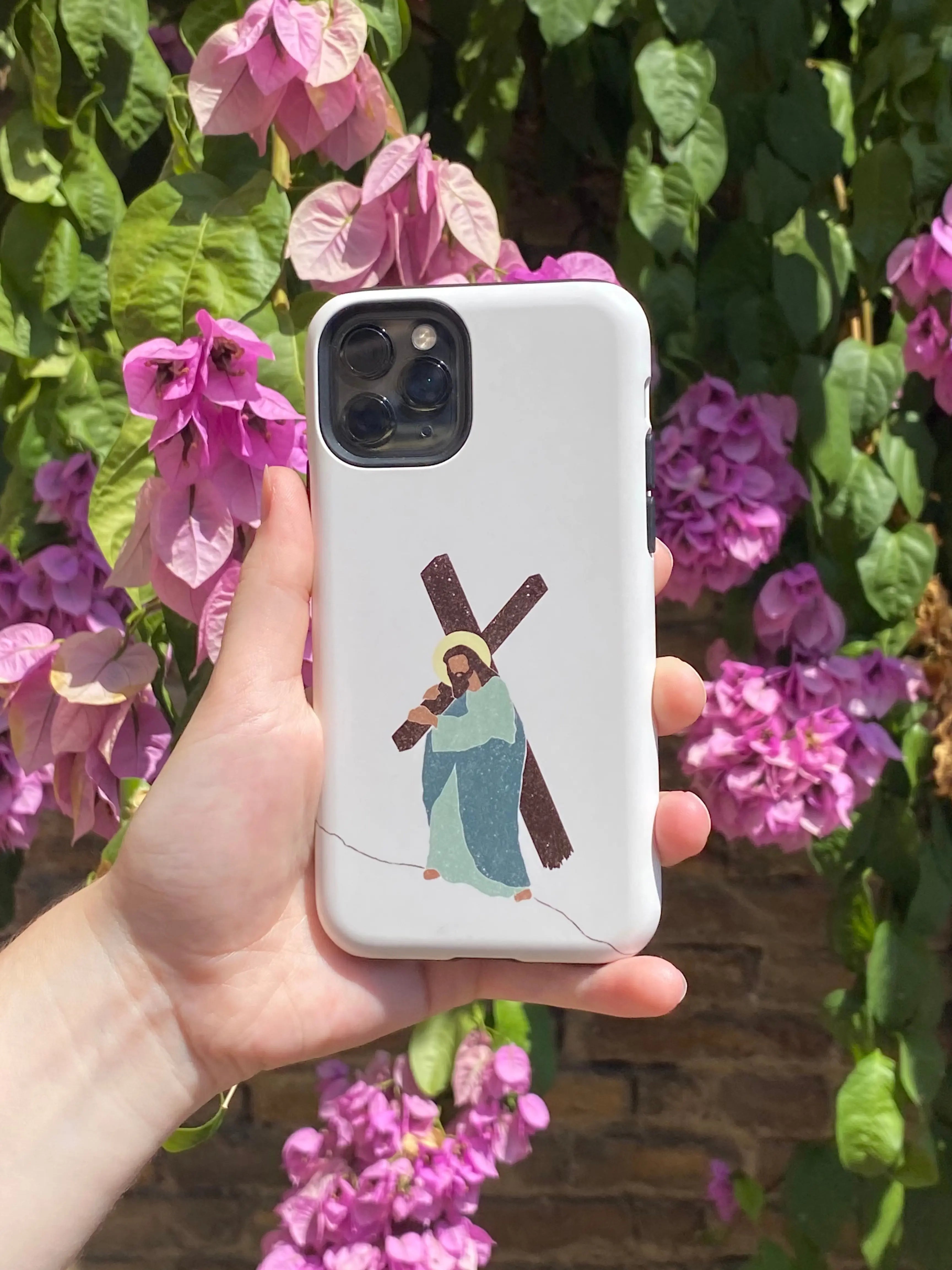 Close-up of a Christian iPhone case featuring a graphic image of Jesus with the cross on a bright floral backdrop.