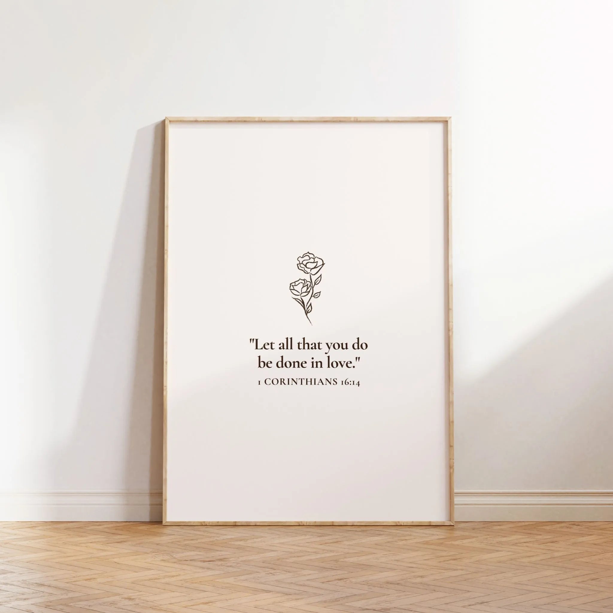 “All things in love” Christian verse printable poster leaning on wall with wood floor.