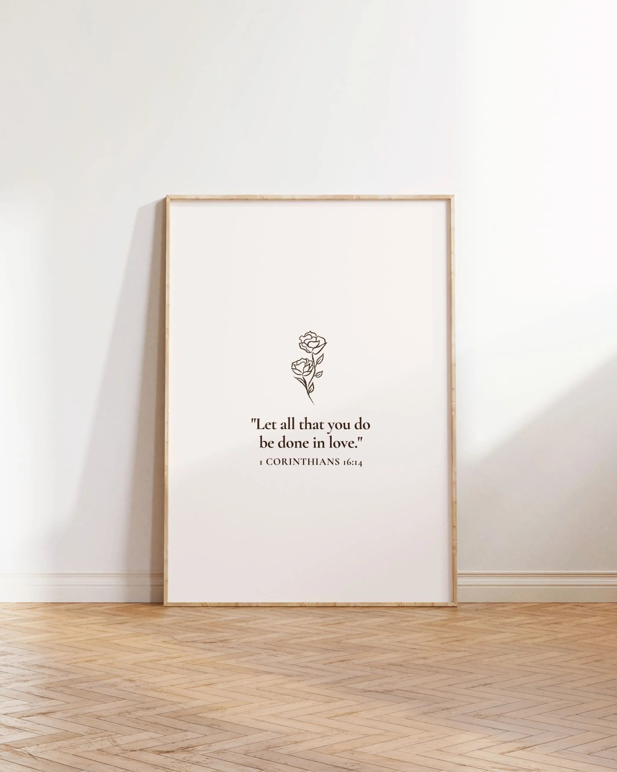 “All things in love” Christian verse printable poster leaning on wall with wood floor.