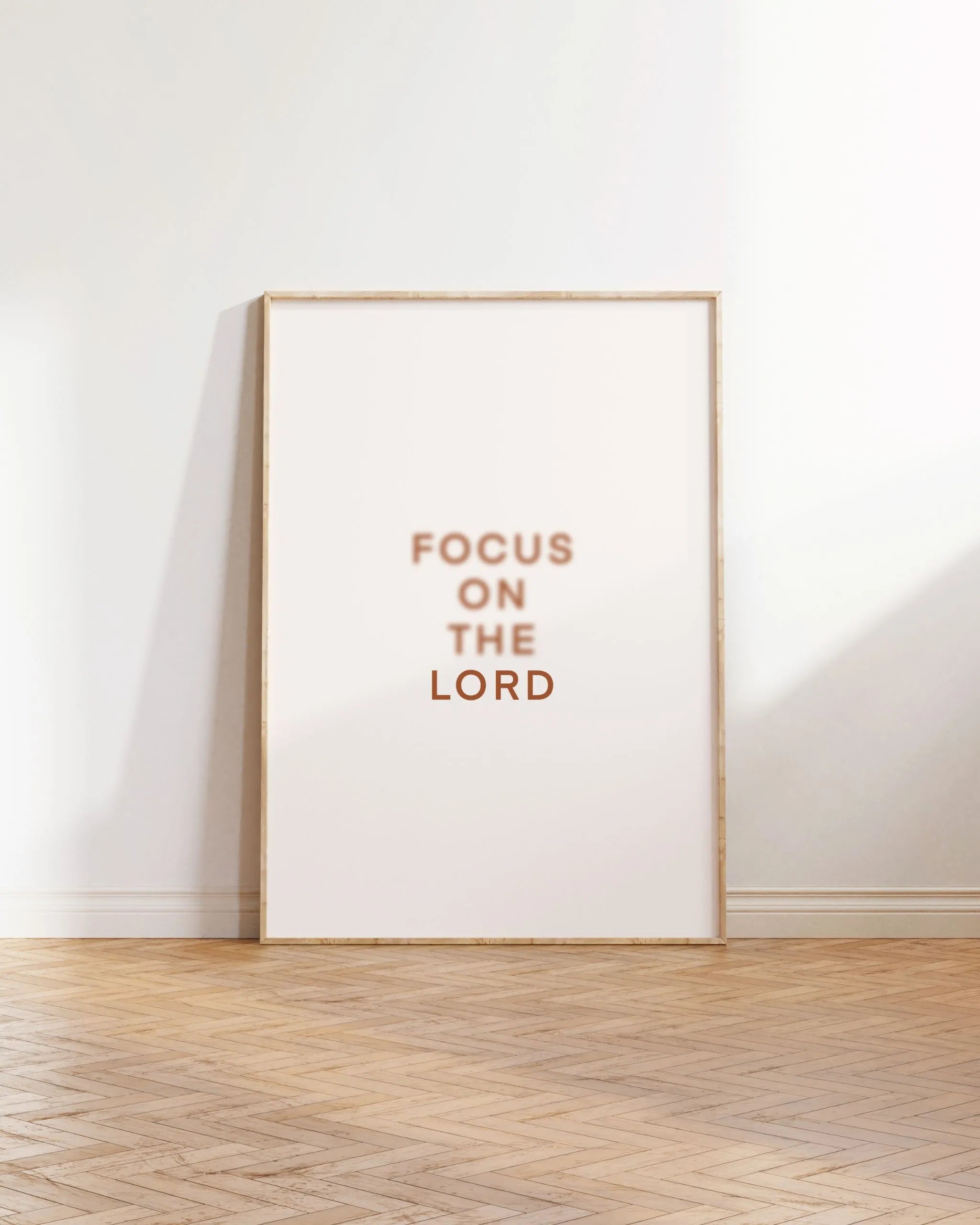 “Focus on the Lord” Christian text art, printable PDF/JPG, lightwood frame on wood floor.