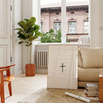 Nail Cross minimalist wall art in lightwood frame near plants, printable Christian décor.